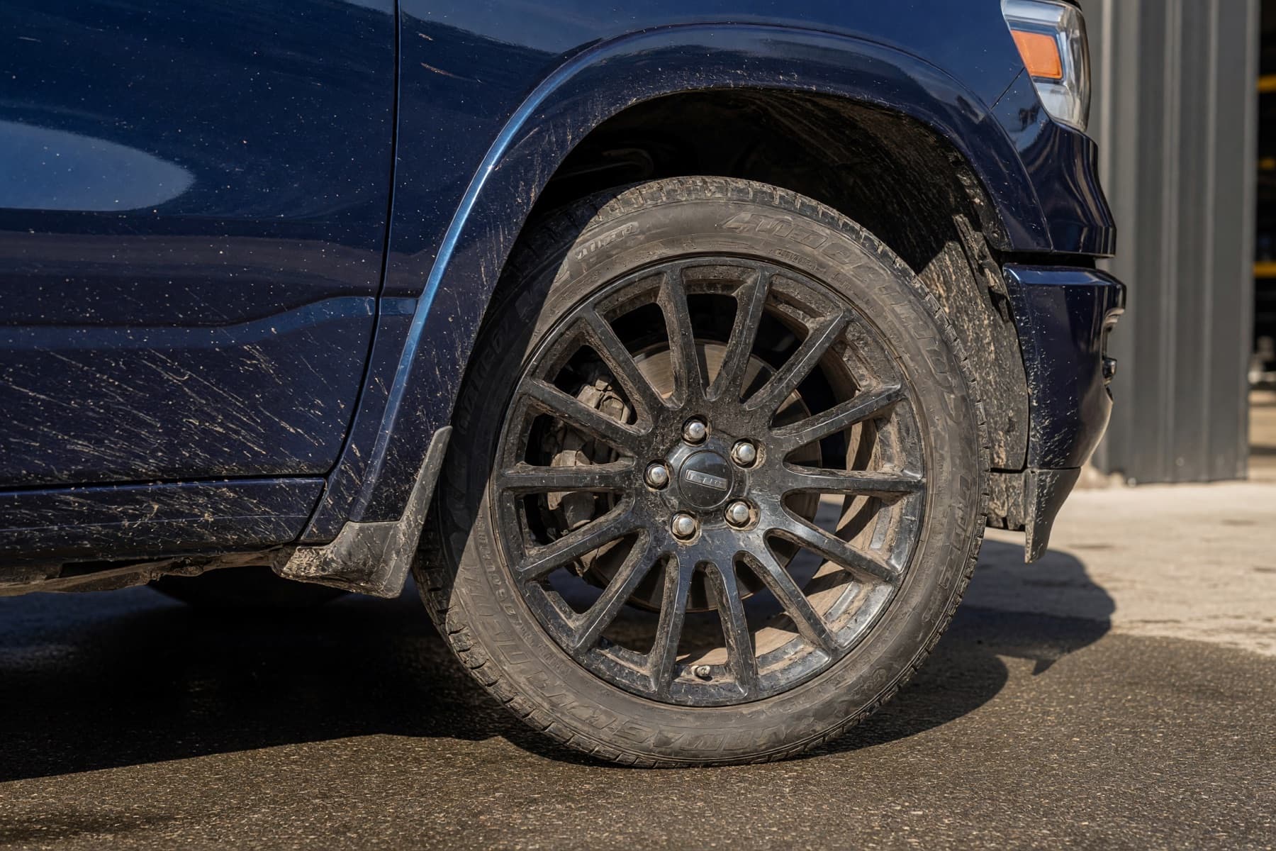 Road grime on a dark blue pickup before detailing